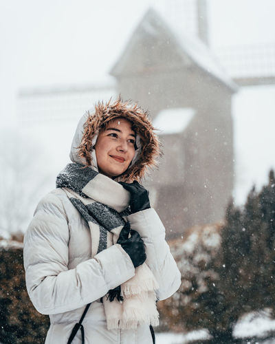 Smiling woman standing in snow during winter