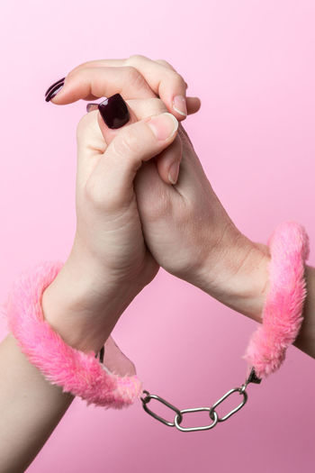 Close-up of woman hand holding pink over white background
