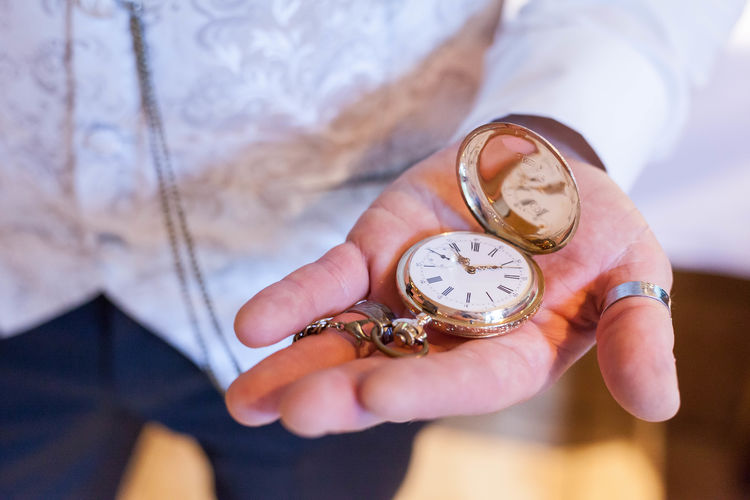 Midsection of man holding pocket watch