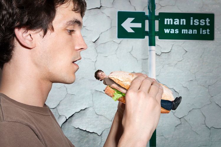 Digital composite image of man having self in burger against damaged wall