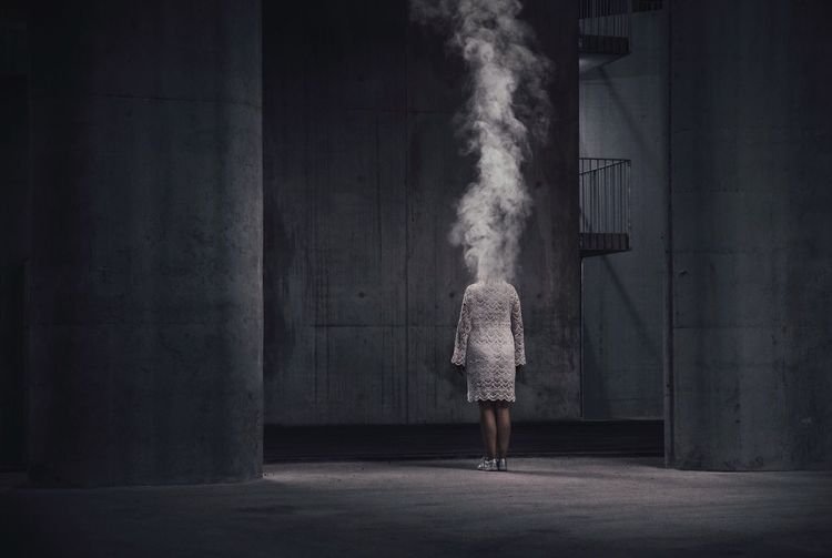 Smoke emitting from woman standing against wall