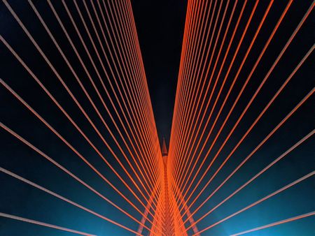 LOW ANGLE VIEW OF ILLUMINATED SUSPENSION BRIDGE AGAINST SKY AT NIGHT