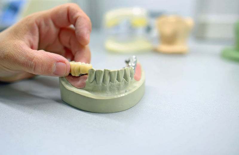 Cropped hand of male dental technician making dentures in laboratory