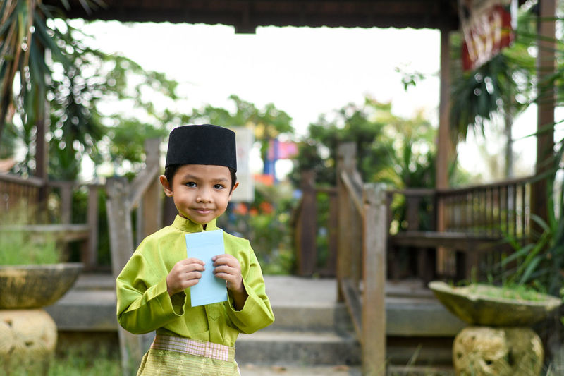 Portrait of cute boy in traditional clothing holding envelop