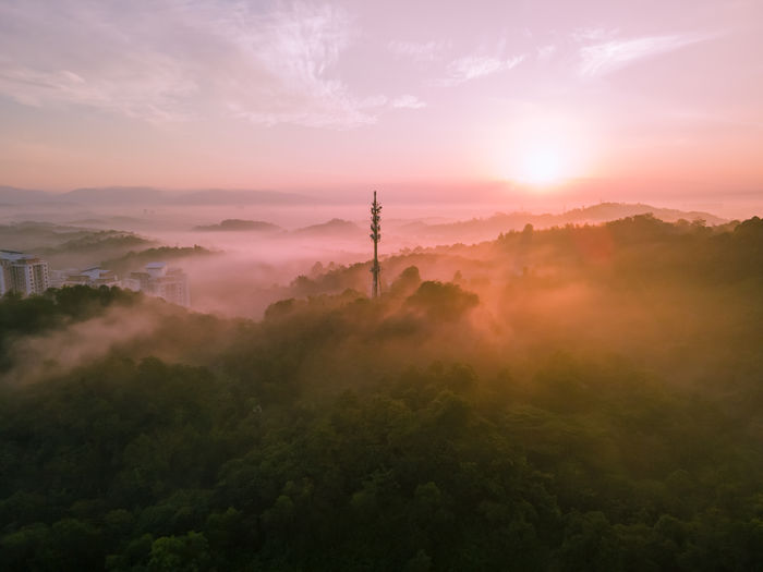 Aerial view of 5g communication tower during beautiful sunrise with clouds