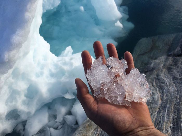 Cropped image of person holding ice by iceberg