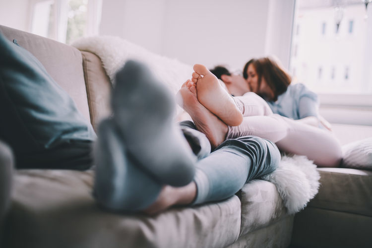 Woman and man kissing on sofa at home