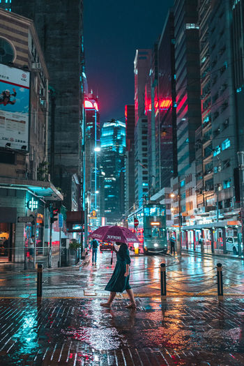 Woman walking on wet street in city during rainy season