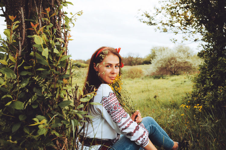 Photo of a smiling young woman in ethnic ukrainian shirt, enjoying the beautiful weekend getaway