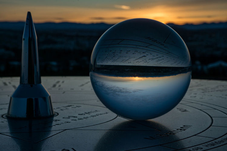 Close-up of crystal ball on table against sea during sunset
