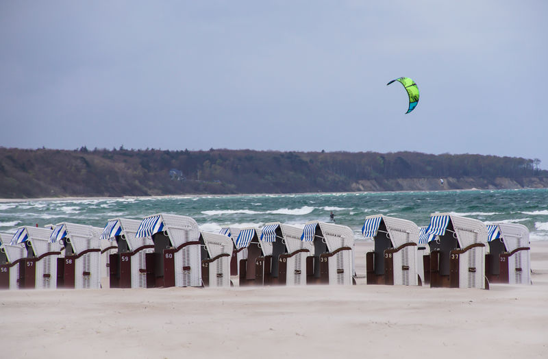 Hooded beach chairs at beach against clear sky