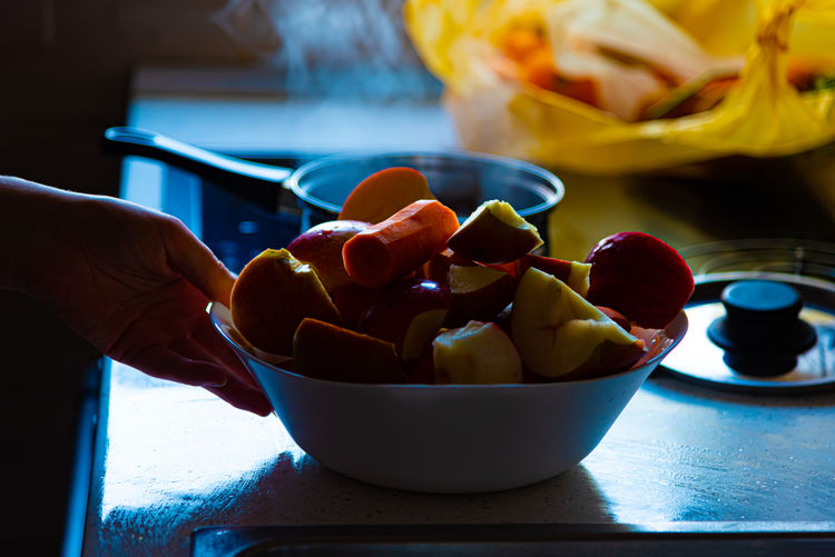Midsection of person holding fruits in bowl on table