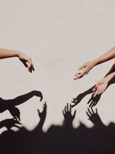 Cropped hands of people gesturing against gray wall