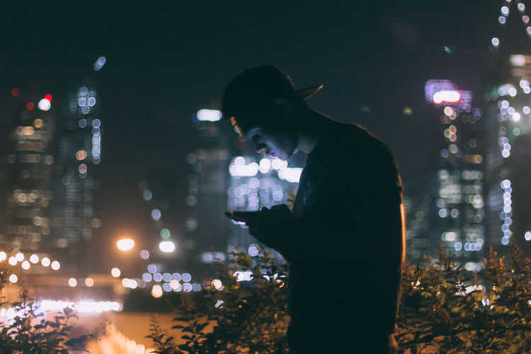 Silhouette man using mobile phone at night