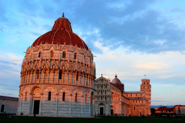 Campo dei miracoli by leaning tower of pisa against sky during sunset
