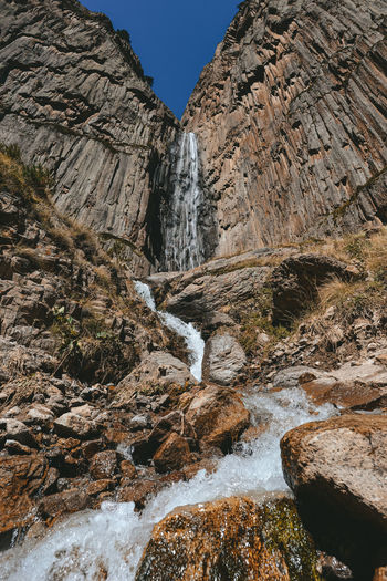 Low angle view of waterfall amidst rocks