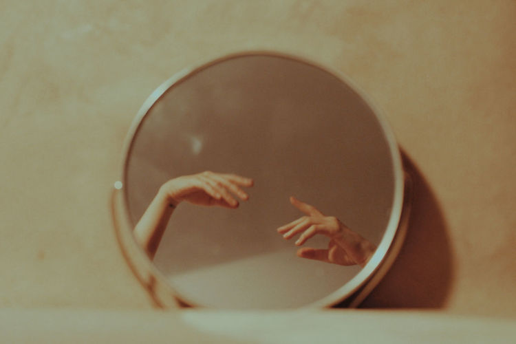 CLOSE-UP OF WOMAN IN MIRROR AGAINST WALL WITH REFLECTION