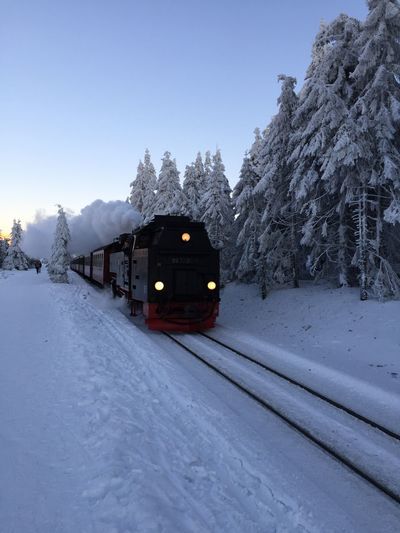 Train on snow covered railroad track against sky