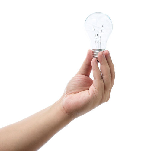 Close-up of hand holding light bulb against white background