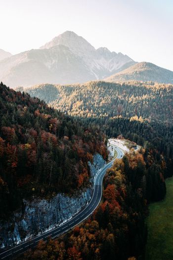 Aerial view of road amidst trees against mountains during autumn