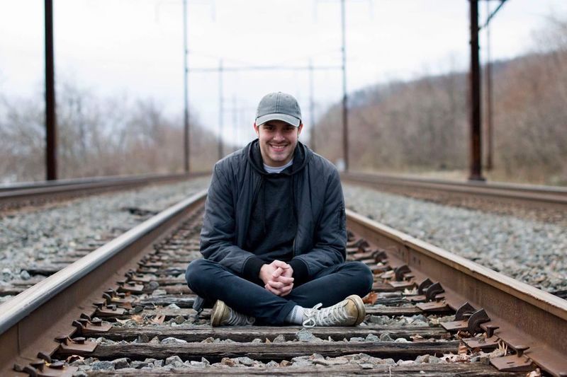 Portrait of happy young man sitting on railroad track