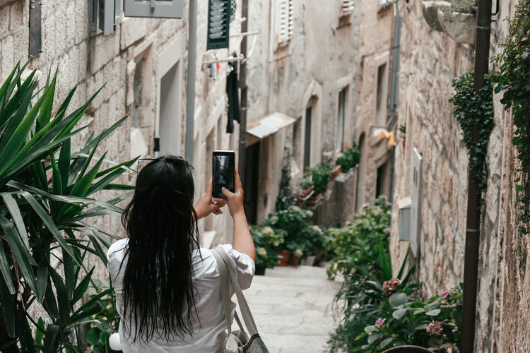 Woman taking photos in narrow street of idyllic old town in korcula, croatia.
