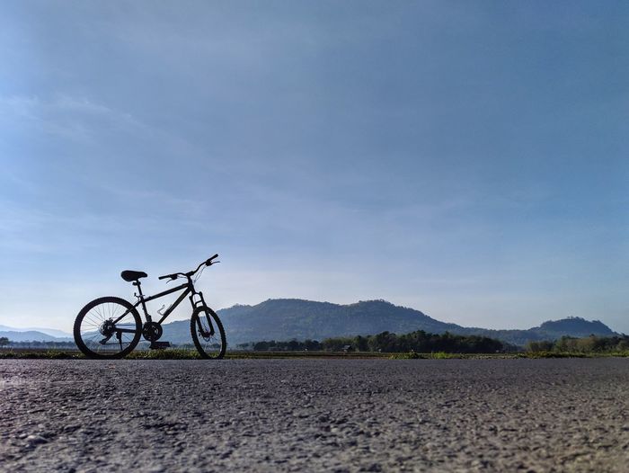 Bicycle parked on land against sky