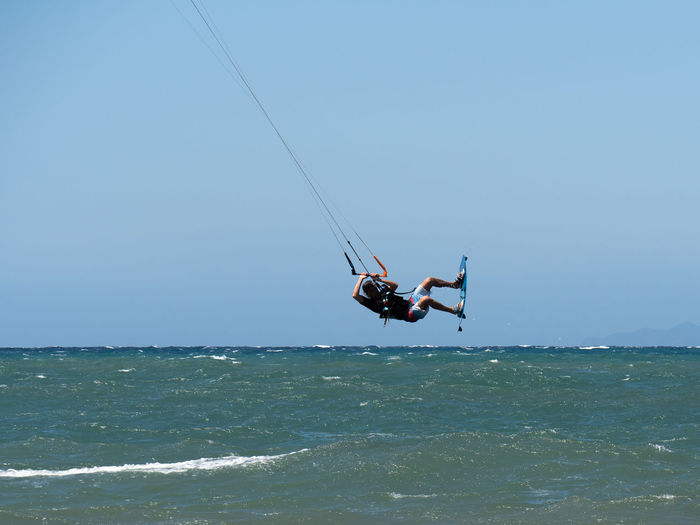 Low angle view of person paragliding in sea against clear sky