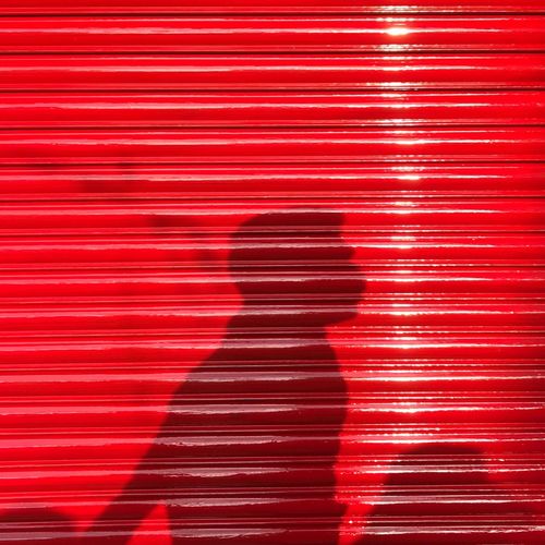 Shadow of man standing on red wall