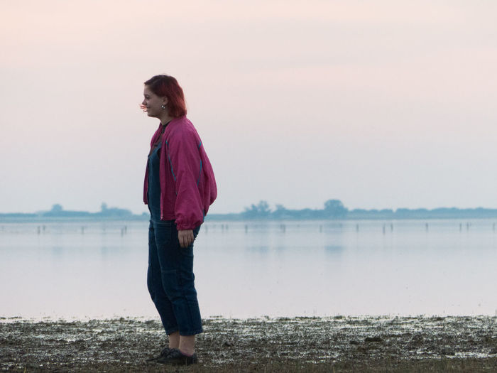 Side view of woman standing on beach against sky
