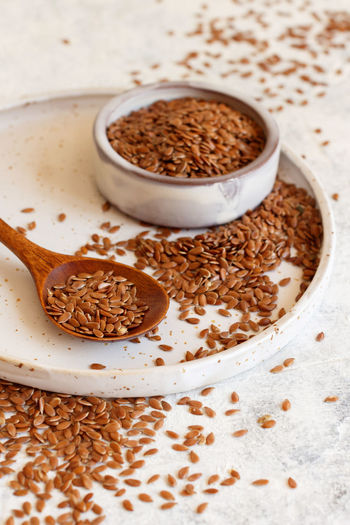Plate of raw flax seeds with a spoon close up