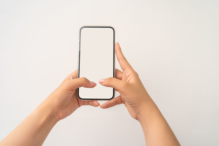 Close-up of hand holding smart phone against white background