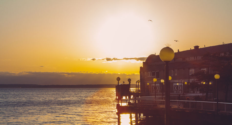 Silhouette built structure by sea against sky during sunset