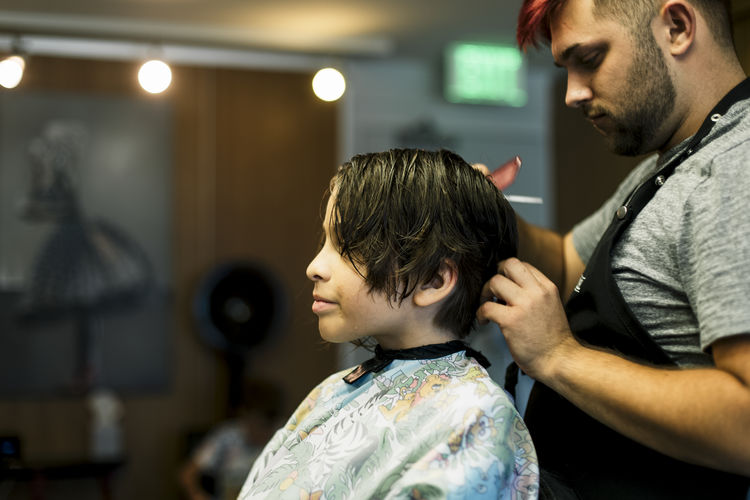 Side view of boy and man cutting hair at salon
