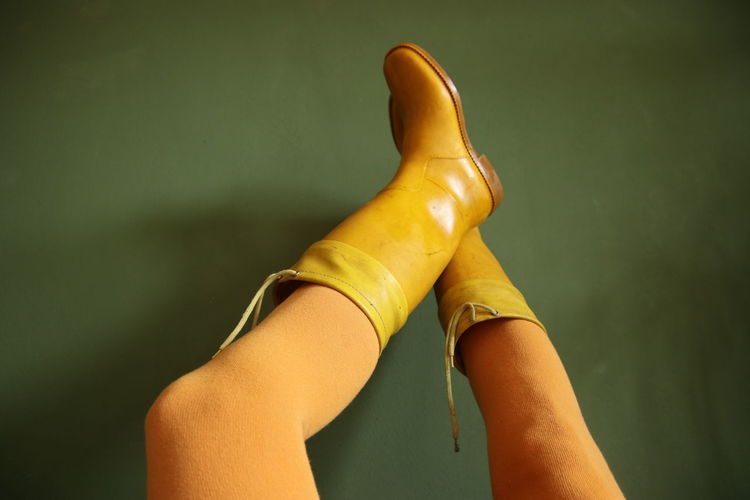 Close-up of human legs with yellow rubber boot 