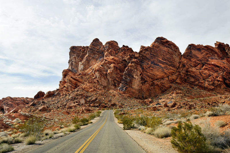 Rock formations by road against sky