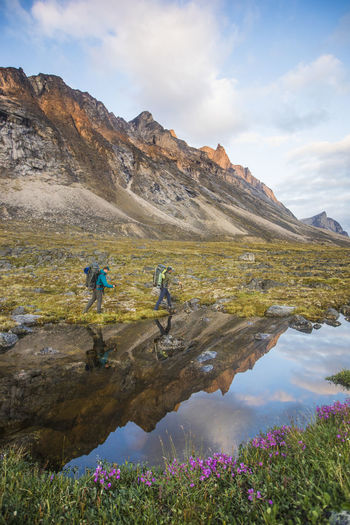 Reflection of backpackers hiking through akshayak pass, canada.