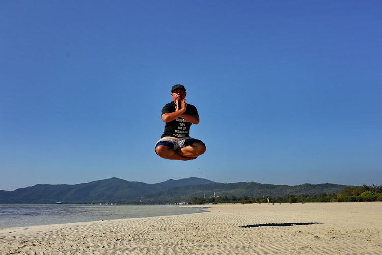 Portrait of man levitating at shore of beach
