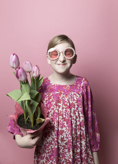 Mod, quirky girl, fair skin, holding pink tulips on pink backdrop