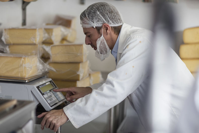Cheese factory worker weighing packaged cheese