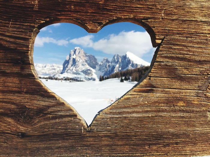 Snow covered mountains seen through heart shape on wood
