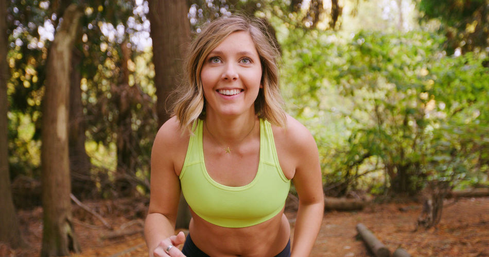 Smiling young woman exercising in forest