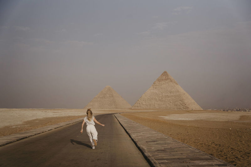 Female tourist running along road leading to giza pyramids