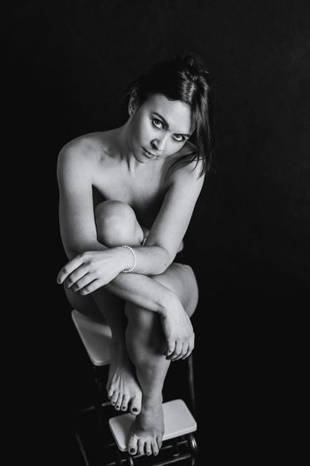 High angle portrait of naked woman sitting on stool