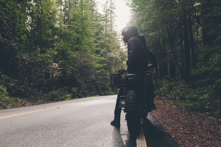 Man riding motorcycle on road amidst trees