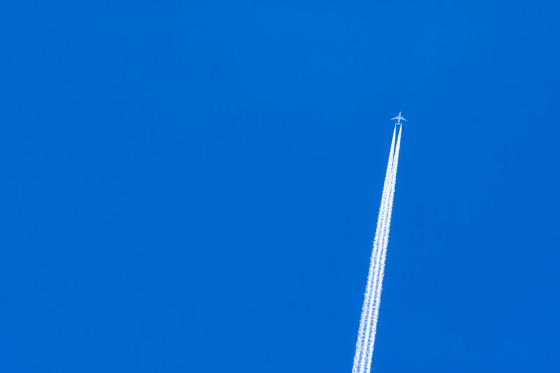Airplane with white condensation tracks. jet plane on blue sky and white clouds with vapor trail. 