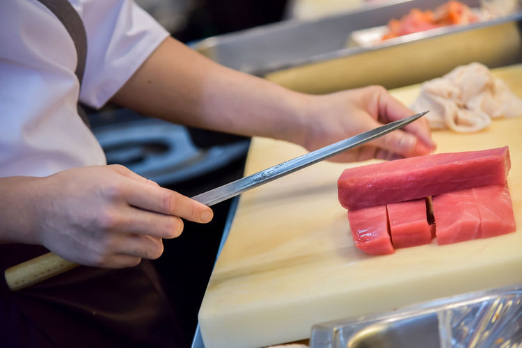 Midsection of chef cutting meat in commercial kitchen