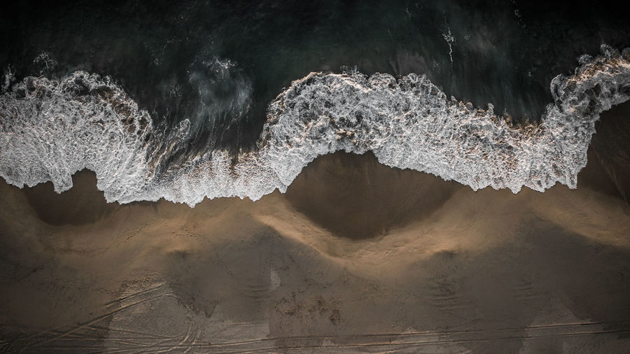 Aerial view of sea waves rushing at beach