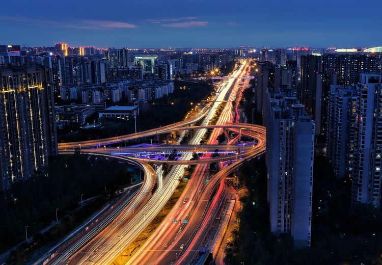 High angle view of light trails on highway amidst buildings