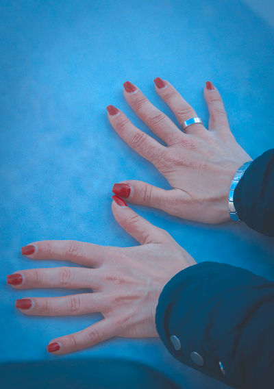 Close-up of woman hand on blue wall